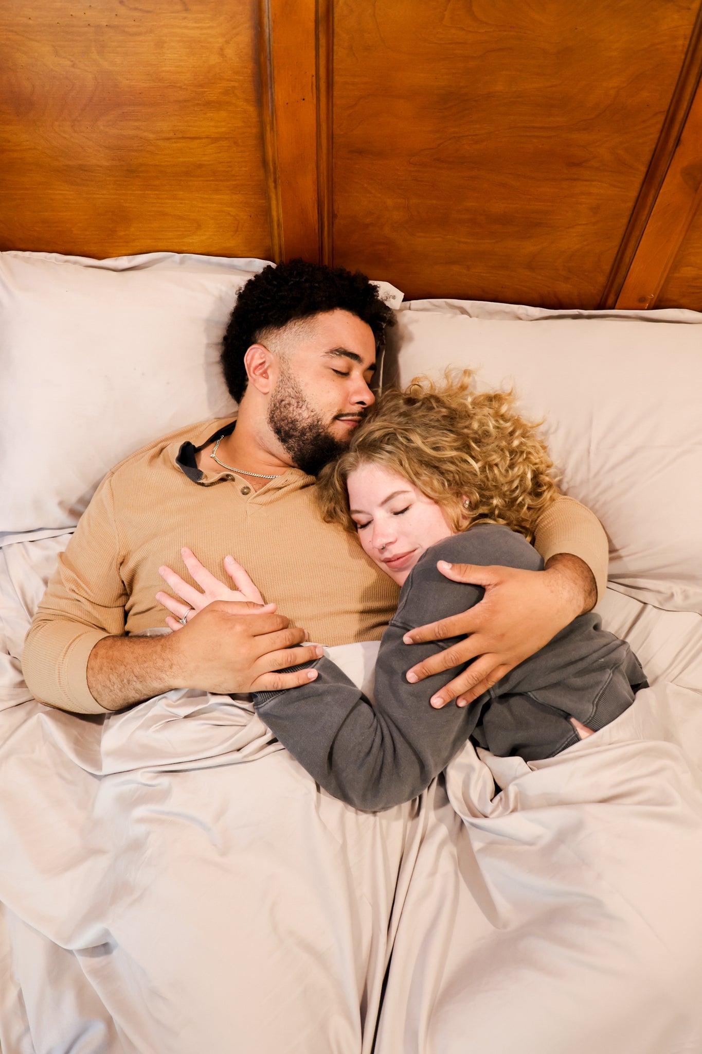 A man and woman embrace affectionately while cuddling together in a cozy bed.