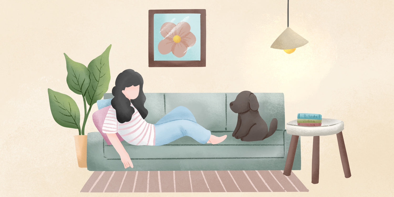 A woman sits comfortably on a couch, gently petting a dog resting beside her, creating a cozy atmosphere.